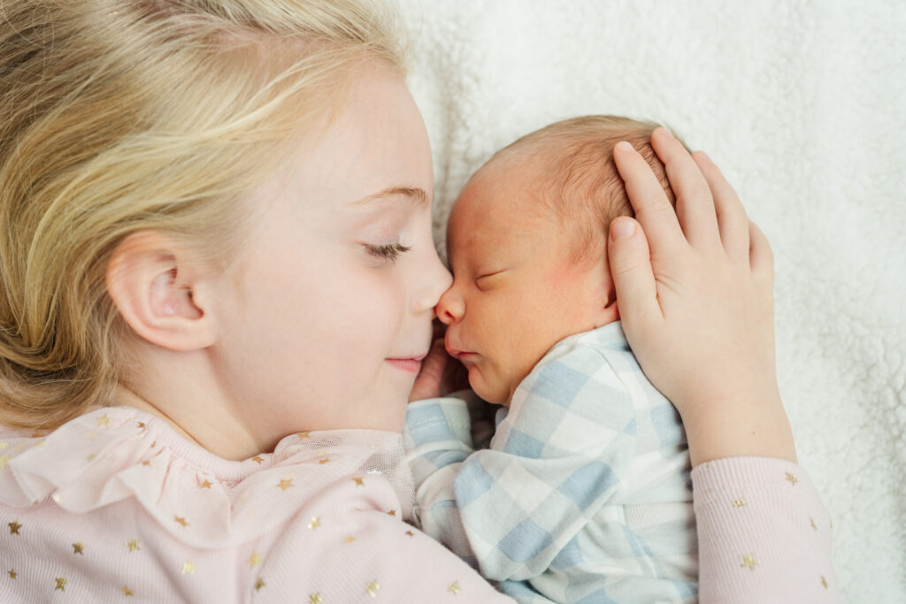 Newborn baby girl sleeping in floral outfit during in home newborn photography session in natural light.