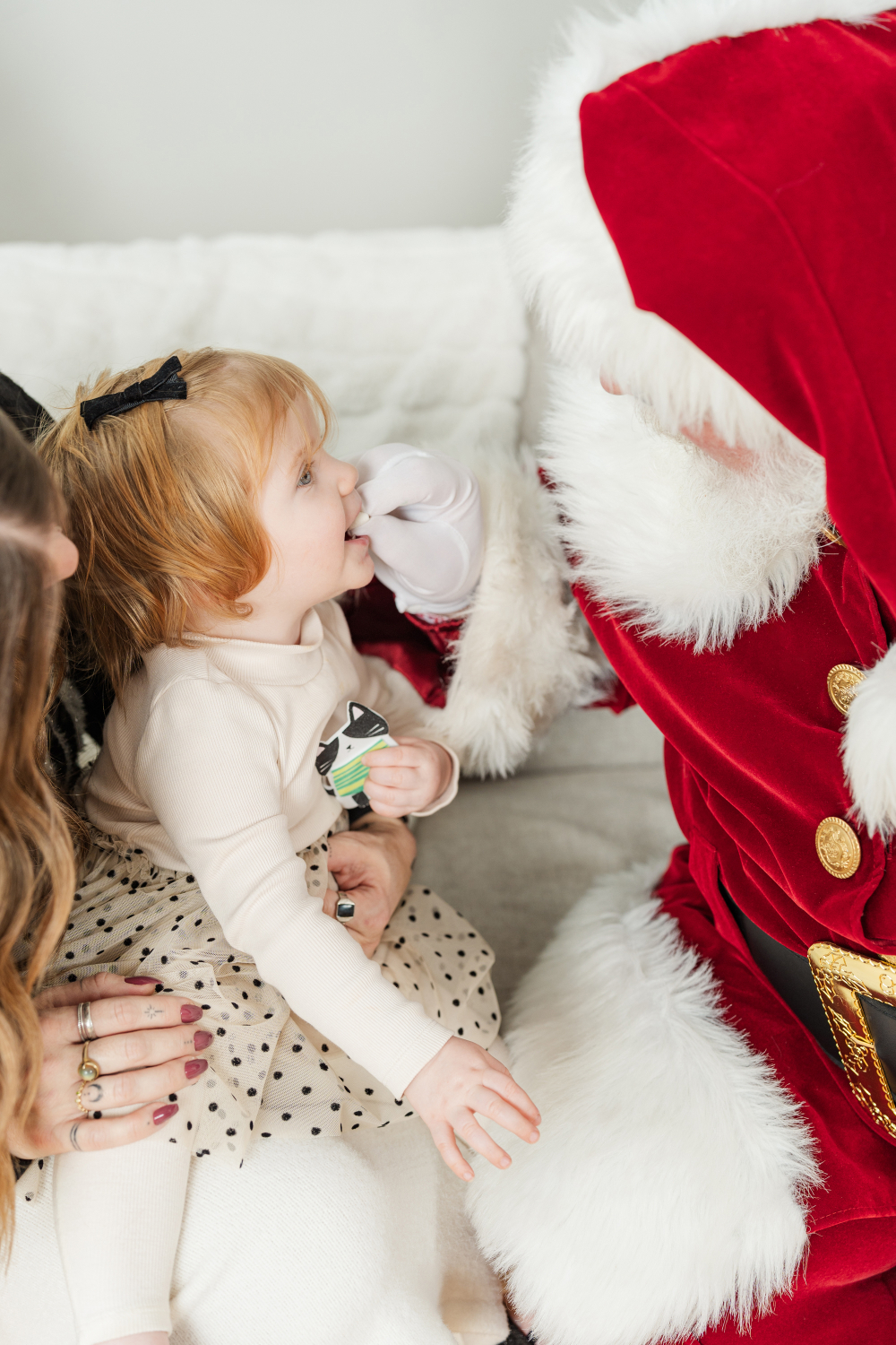 Young girl smiling up at Santa during professional Santa photos in Minneapolis holiday studio with cozy details.