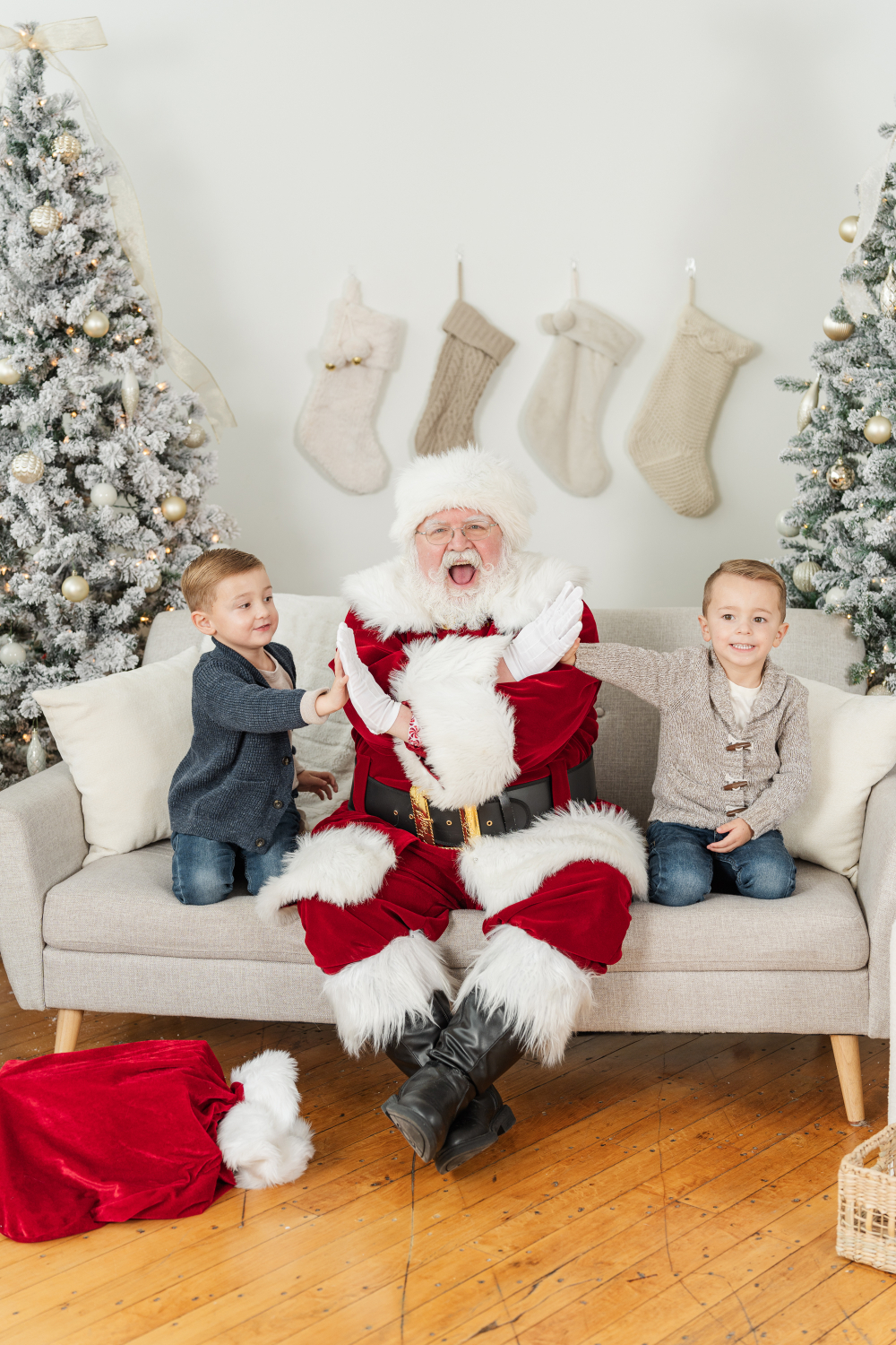 Santa laughing with two young boys during professional Santa photos in Minneapolis holiday studio with festive decor.