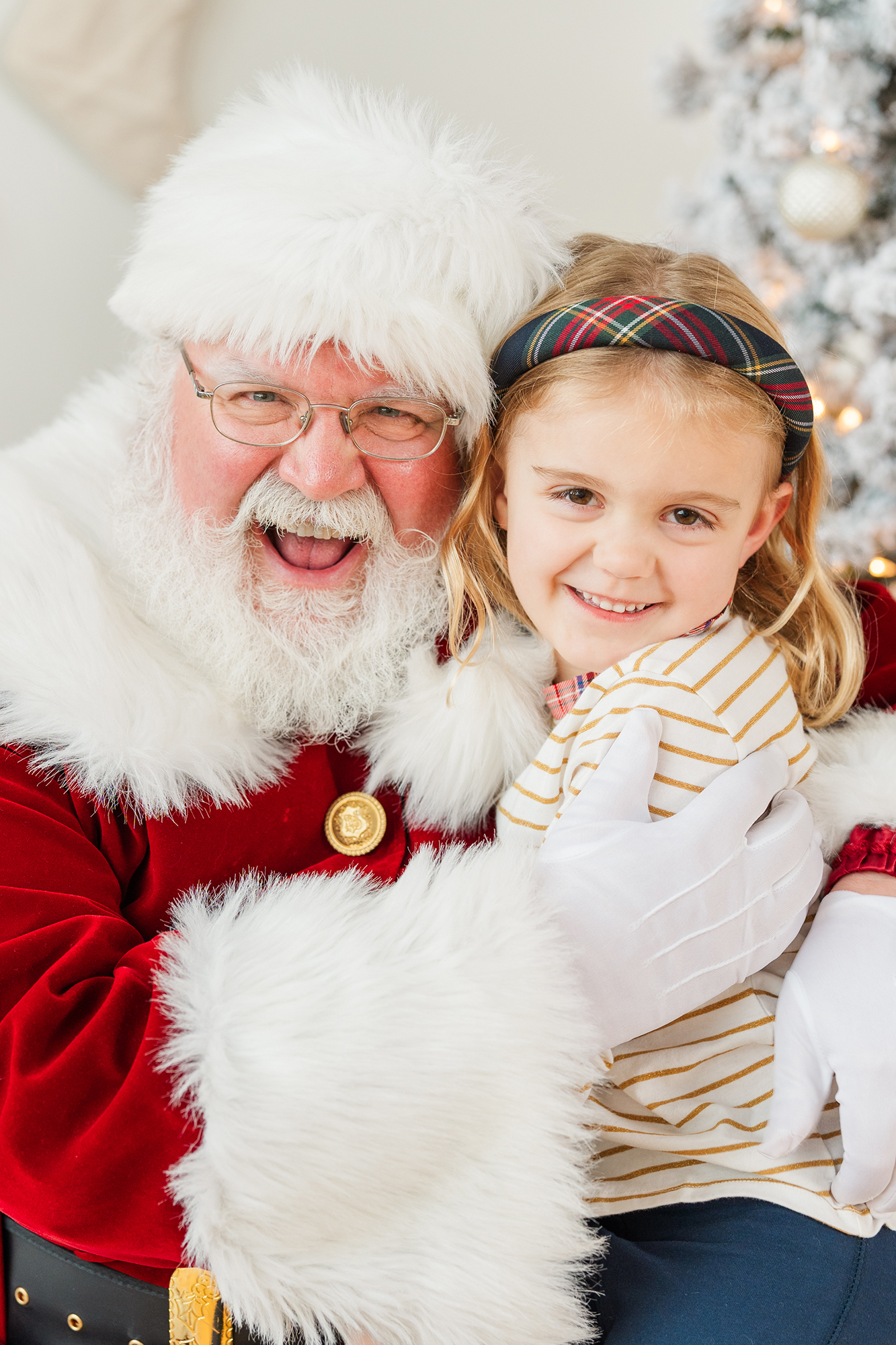Santa smiling with a young girl during professional Santa photos in Minneapolis holiday studio with festive decor.