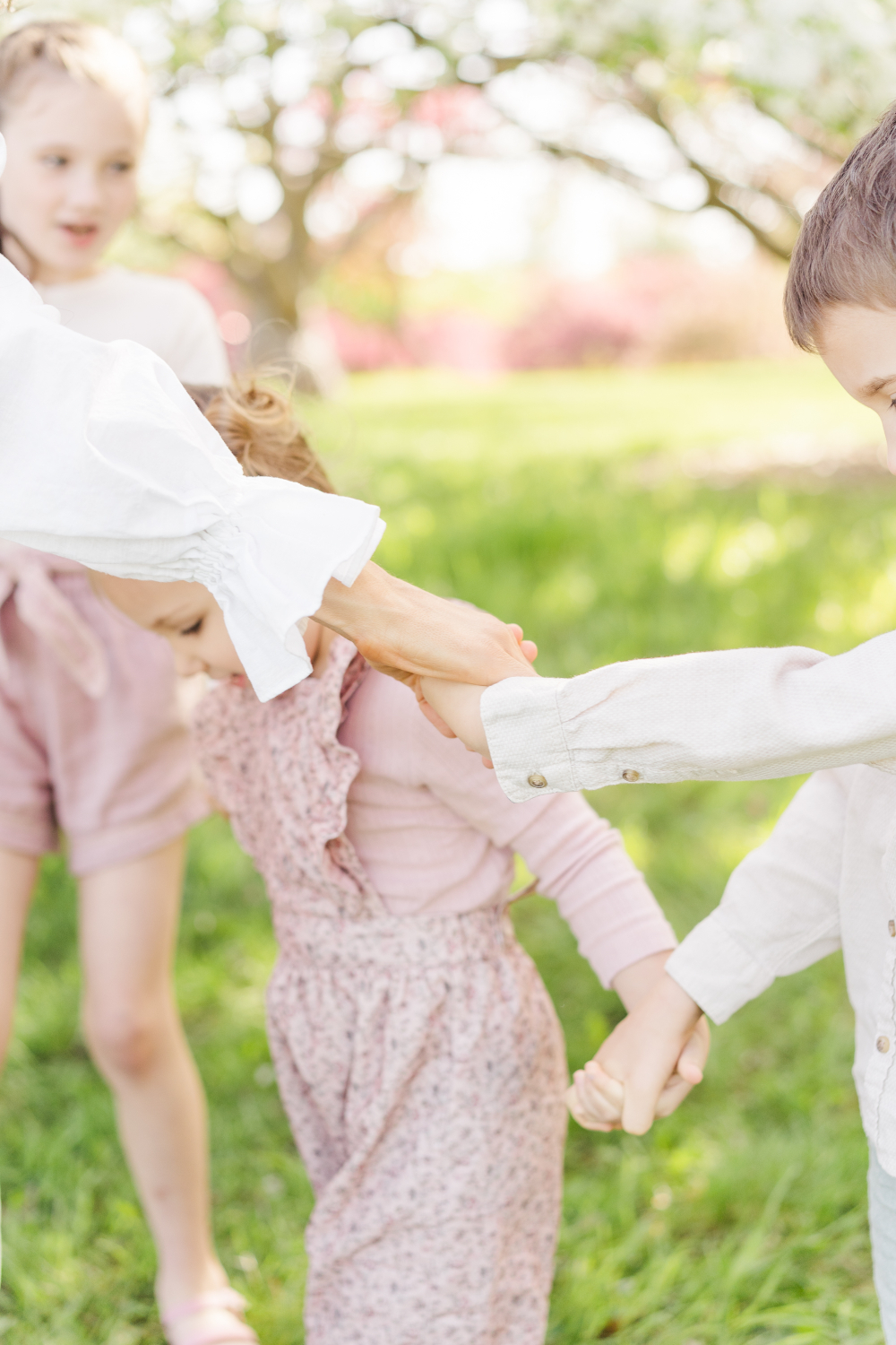 Children and parent holding hands while playing outside, capturing a sweet and connected family moment.