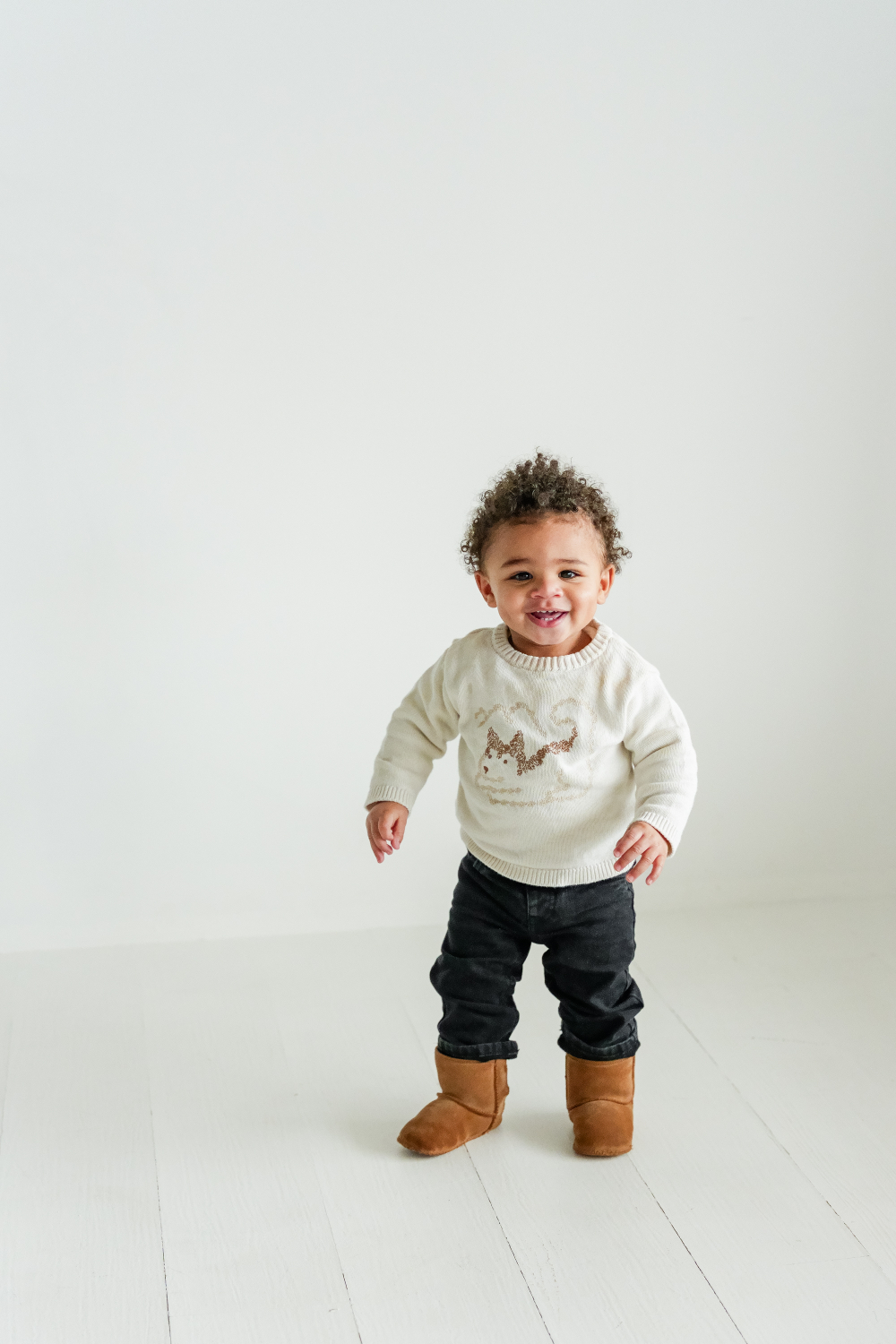 Smiling toddler standing confidently in studio; a joyful moment captured during a toddler photoshoot session.