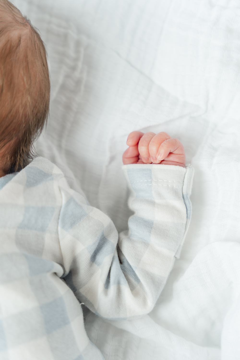 Minnesota newborn photographer captures sleeping newborn in soft blue outfit with tiny curled hand.