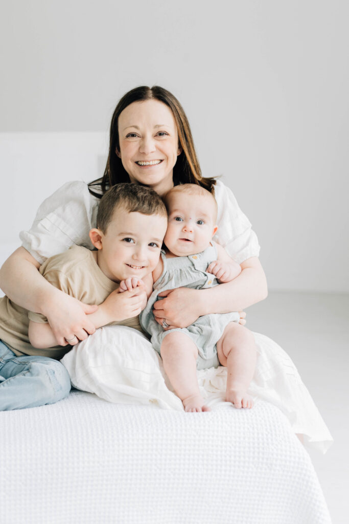 Photos I never want to live without: smiling mother holding her two children during a bright studio motherhood portrait.