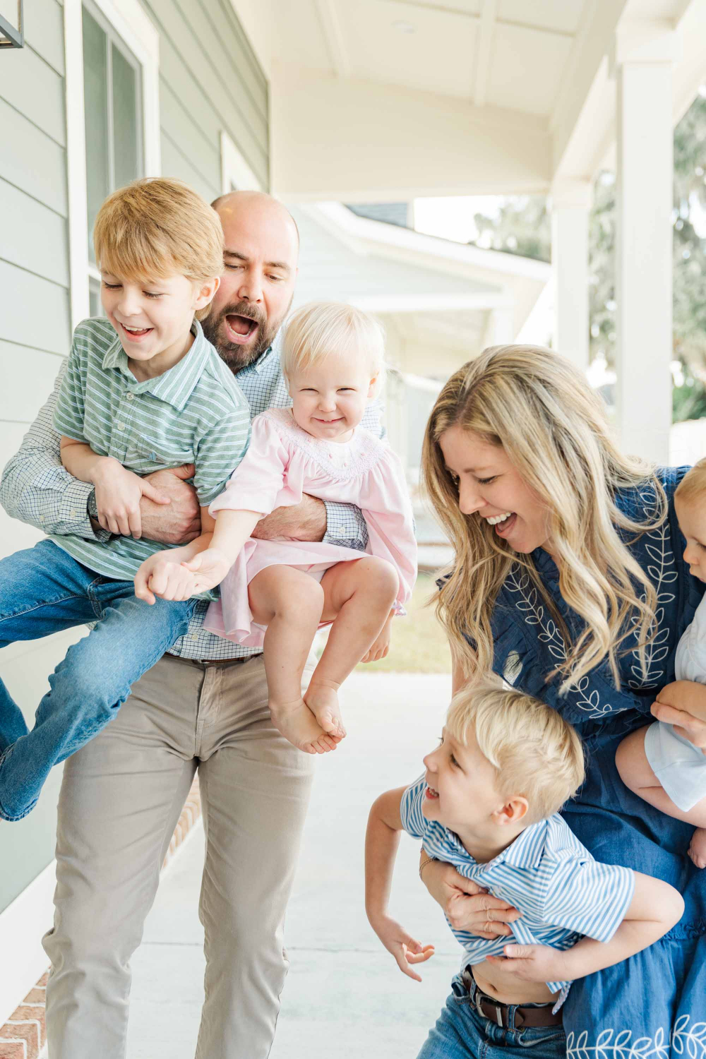 Happy family laughing and cuddling together indoors, showcasing natural connection and what to wear for family photos