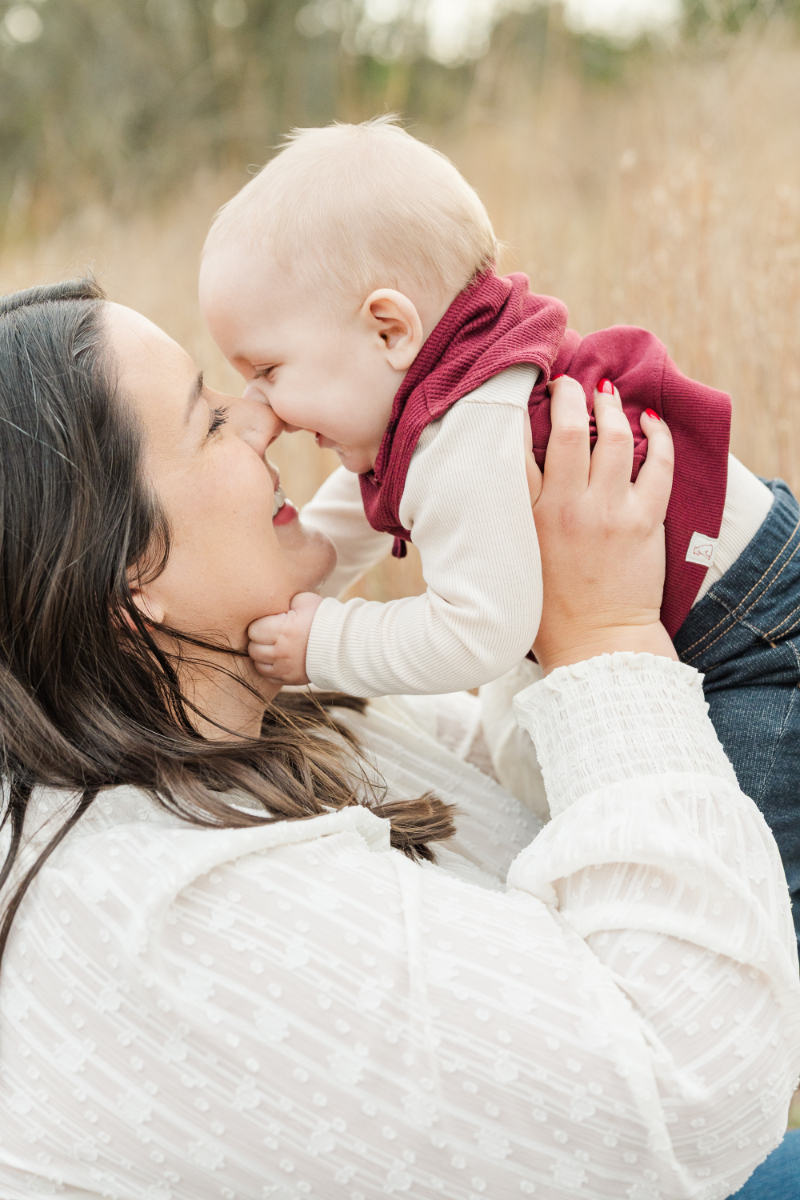 Mother’s Day gift ideas with mom lifting baby close during warm, candid outdoor family photo session