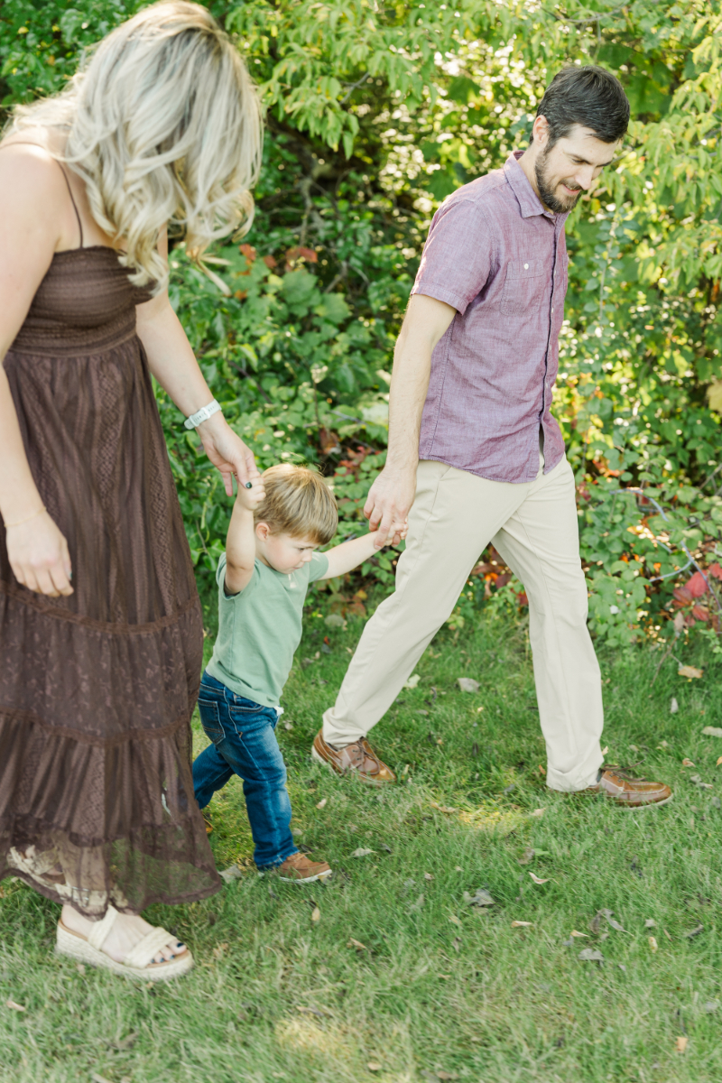 Mother’s Day gift ideas with parents holding toddler hands during outdoor family photo session in Minneapolis