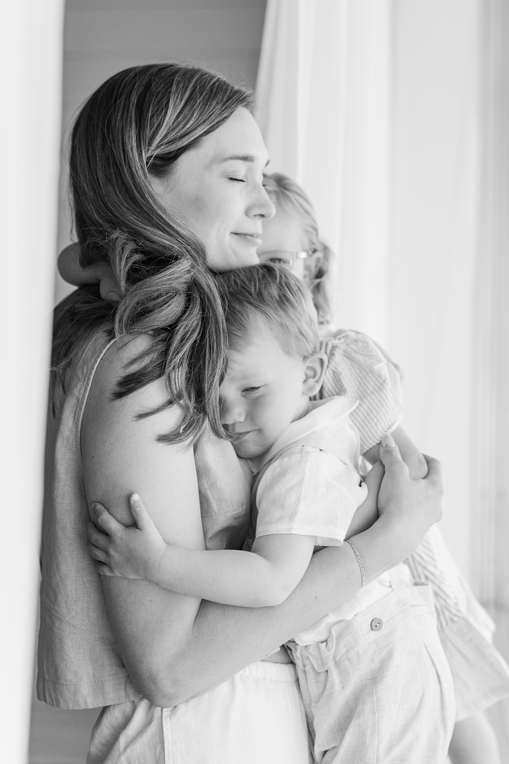 Mother’s Day gift ideas with mom hugging children close during soft, emotional black and white family photo session