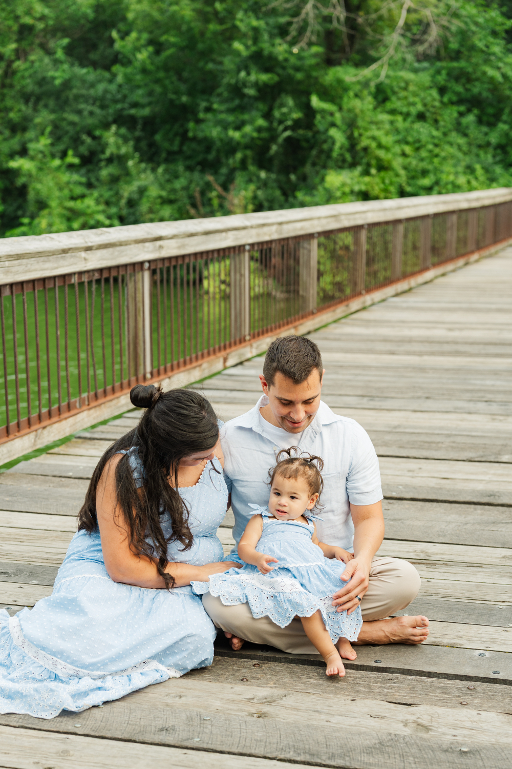 Family sitting together on wooden bridge, soft moment captured in natural Minneapolis photo places setting