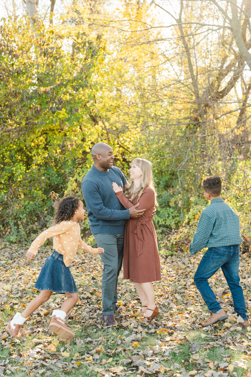 A family shares a playful moment together as their children run around them in a sunlit field. These golden hour photos capture movement, laughter, and connection, creating authentic family portraits filled with warmth and energy.