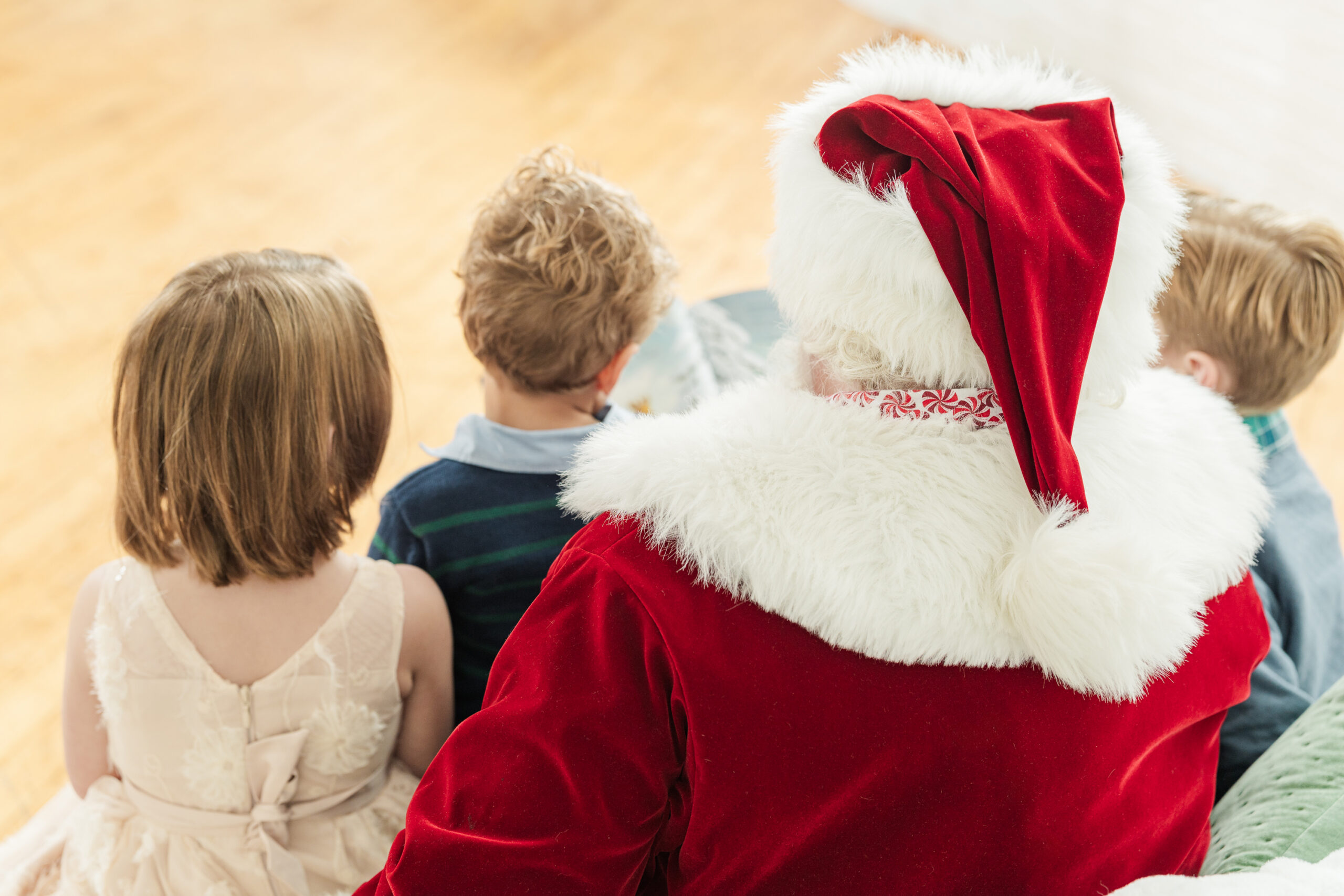 Santa reading a Christmas story to three children during a holiday photo session, with classic christmas photo outfits creating a warm and magical family memory.
